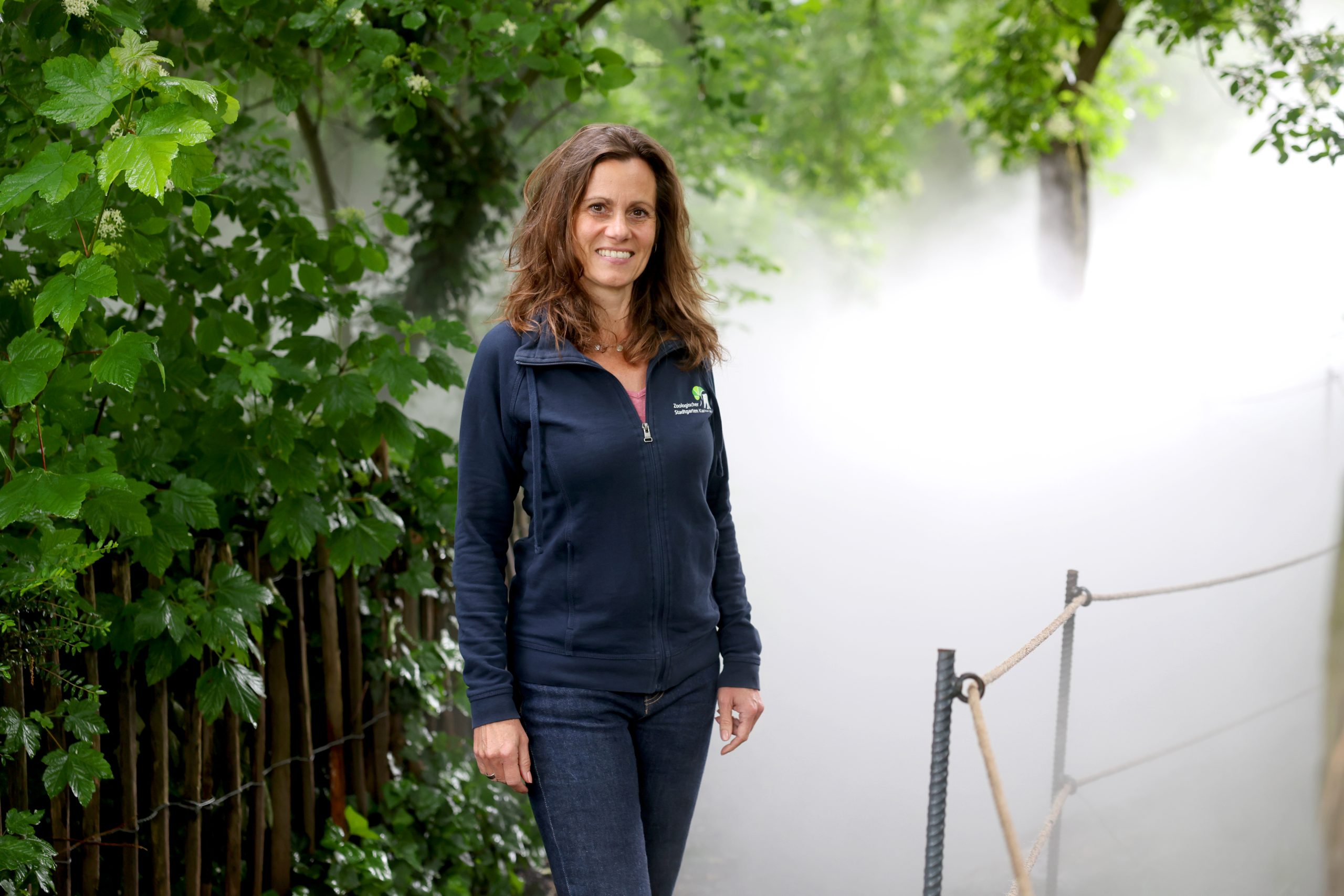 Architektin Anja Wurm steht mitten im Nebel des Farngartens. Foto: Timo Deible/Zoo Karlsruhe